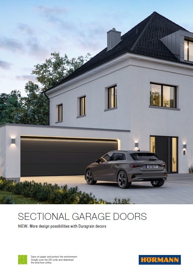 A car parked in front of a house featuring dark grey sectional garage doors.